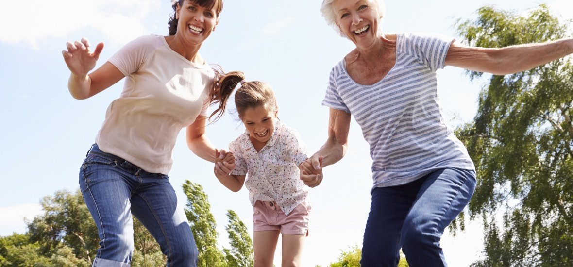 Grandmother, Granddaughter And Mother Bouncing On Trampoline